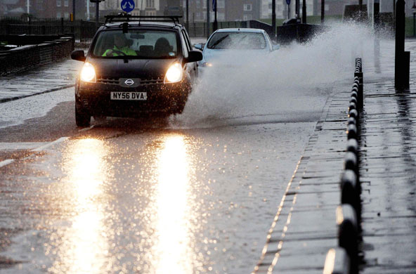 wet weather uk: Whitley Bay: A car drives along a flooded road