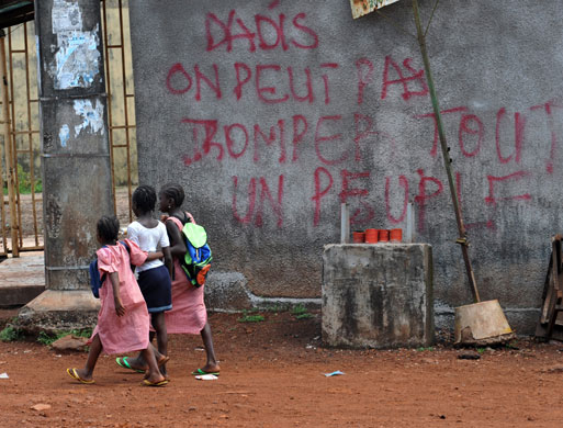 Guinea unrest: Schoolgirls walk near a building covered with graffiti