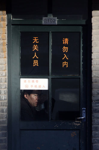24 hours in pictures : Policeman looks out of a window as he talks on a phone in China