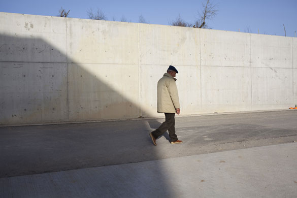 L'Aquila - 7 months later: A man walks past a newly built wall in the village of Sassa