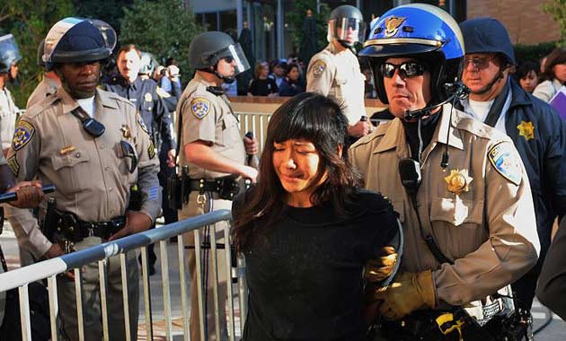 A student protester is detained by police officers