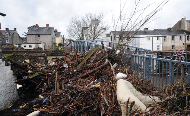 Cockermouth clear-up: Debris piled up against a closed footbridge after flood water receded