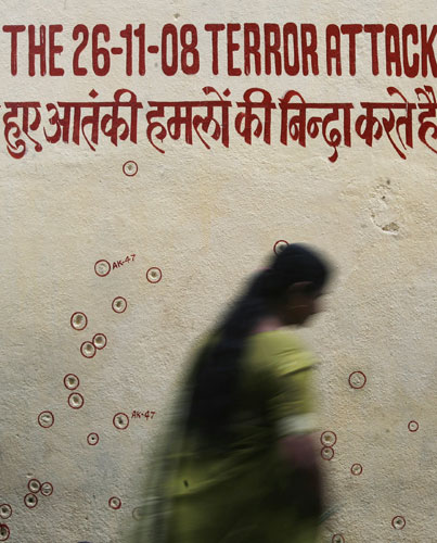 Mumbai attack anniversary: A woman walks past a wall riddled with bullet holes at Nariman House