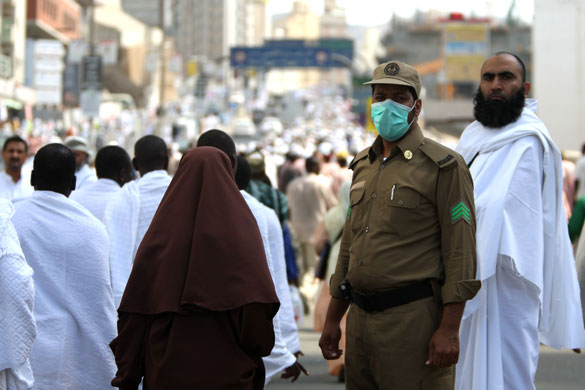 Mecca Hajj: A Saudi security official wearing a protective mask watches Muslim pilgrims