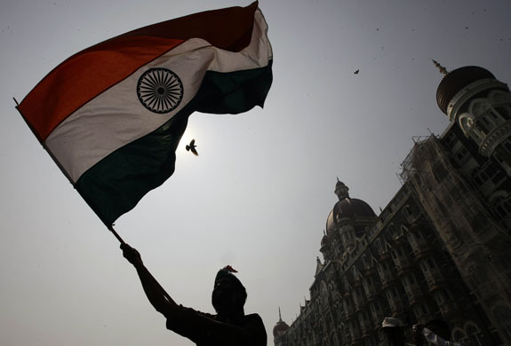 Mumbai anniversary: A man waves a flag outside the Taj Mahal hotel