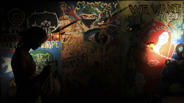 Mumbai anniversary: A woman walks in front of a painting  in remembrance of the victims