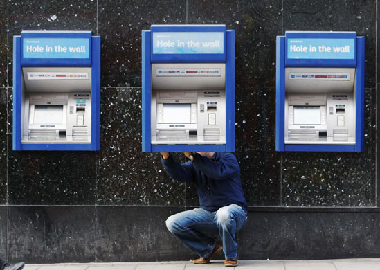 Week in business: A man repairs a cash machine outside a bank in London