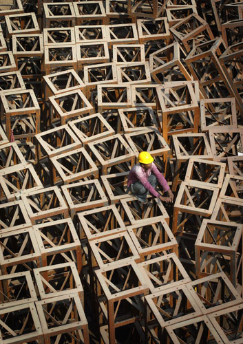 24 Hours in Pictures: A worker sits on iron beams at the construction site in Chennai