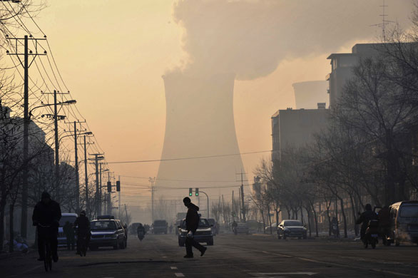24 Hours in Pictures: People walk near a coal-fired power plant in Shenyang, China