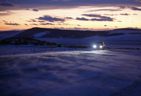 24 hours: Novosyolovo, Russia: A car moves along a highway, at sunset in Siberia