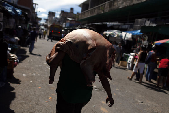 24 hours: Tegucigalpa, Honduras: A man carries a pork in the Las Americas market