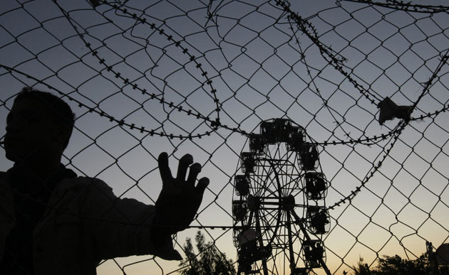 30 November 2009: Gaza City, Gaza: A boy stands by a metal fence at a funfair