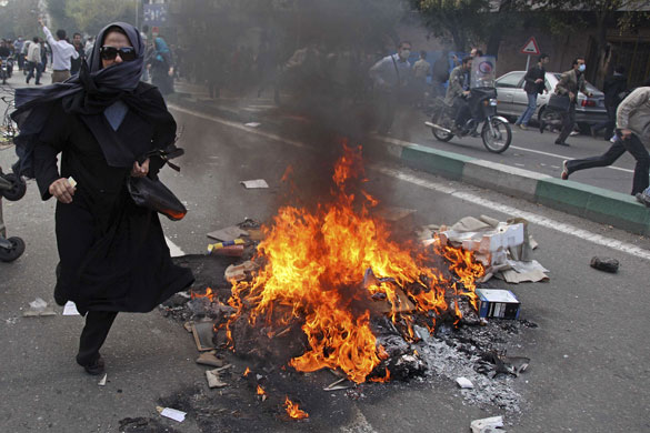 Iran protests: An anti-government female protester runs away from security at a protest