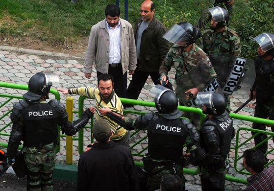 Iran protests: Iranian riot and plainclothes policemen detain a man during protests