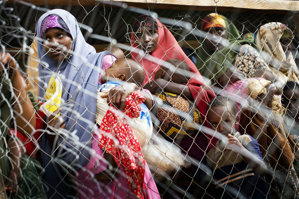 24 hours: Dadaab, Kenya: Somali women wait behind barbed wire at a feeding centre