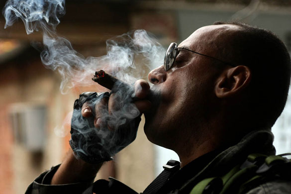 Slums in Rio De Janeiro: Torres smokes a cigar during police raid, Complexo do Alemao