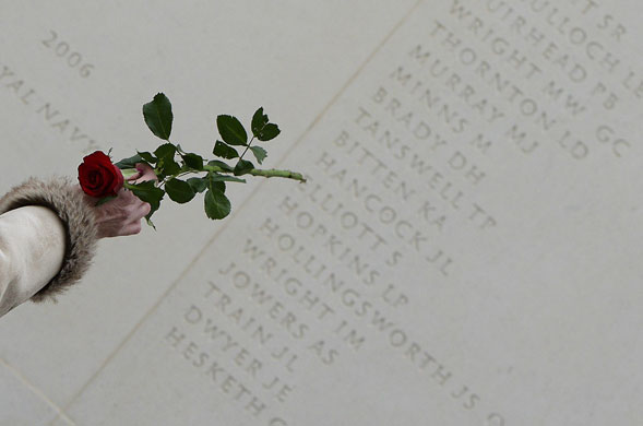 Remembrance Sunday: A visitor holding a rose points to a name on the Armed Forces Memorial