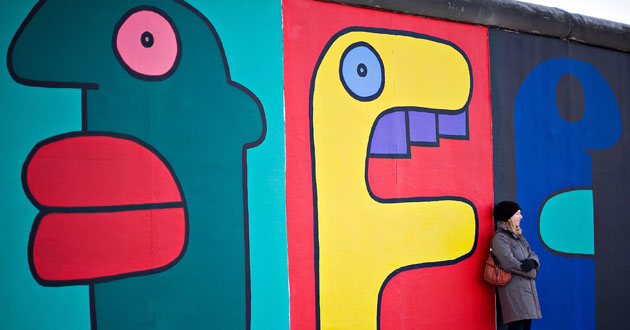 Berlin Wall celebrations: A tourist poses against one of the murals painted on the Berlin Wall