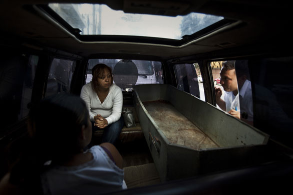 Guatemala morticians: A funeral salesman explains paperwork to the relatives of a murder victim