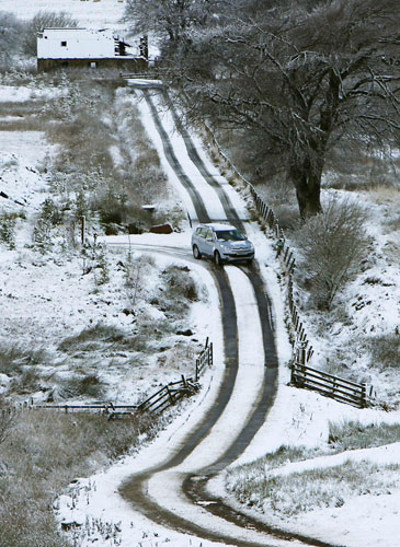 Winter weather: A car travels down a snow covered country road in Penicuik near Edinburgh