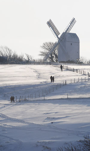 Snow in the UK: People walk in the snow in front of the Jill windmill at Clayton