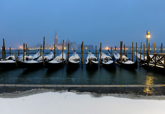 Snow around the world: Snow-covered gondolas moored in Venice's lagoon, Italy
