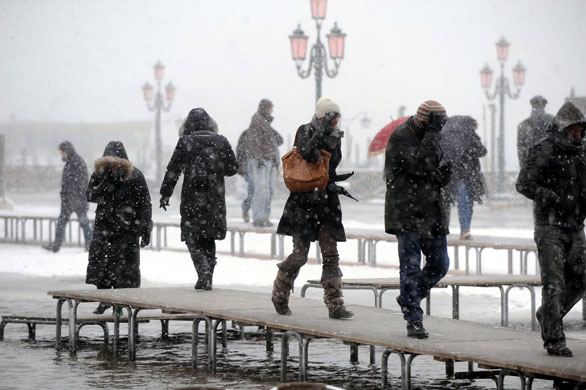 24 hours in pictures: Venice, Italy: Tourists walk on platforms in St Mark's square as snow falls