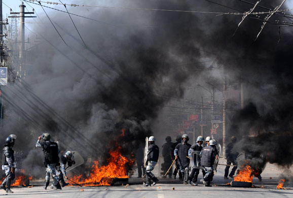 24 hours in pictures: Kathmandu, Nepal: Nepalese police officers remove burning tyres