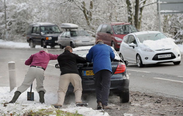 Travel chaos: Three men attempt to push a car from the side of the road in Basingstoke