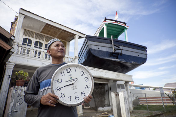 Banda Aceh: Aceh Mujiburrizal holds a clock showing the time his house was flooded