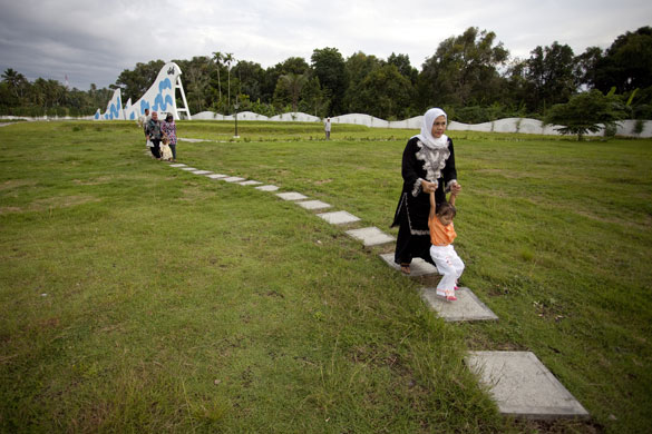 Banda Aceh: Armiati, aged 40 and her child walk through the Lambaro mass grave