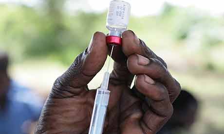 A community vaccinator prepares to inoculate young people in Katine