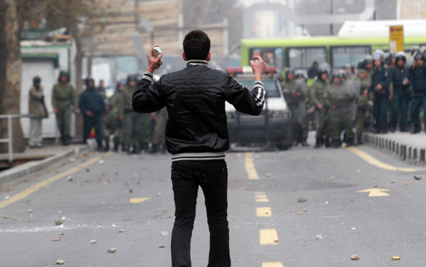 Iran: A protester holds stones as he stands opposite security forces