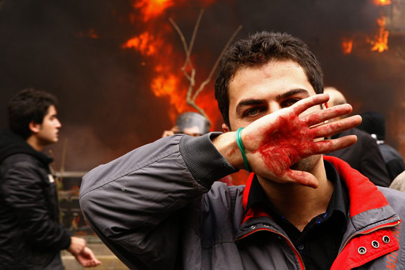 Iran protest updated: An Iranian opposition supporter covers his face in Tehran