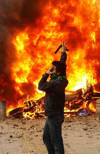 Iran protest updated: Iranian opposition supporter gestures next to a burning police motorcycle