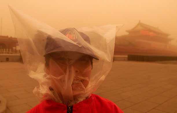 2002-03: 2002, Beijing: A woman covers her head with a plastic bag in a sandstorm