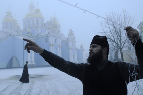 24 hours: Kiev, Ukraine: A Ukrainian Orthodox priest decorates a Christmas tree