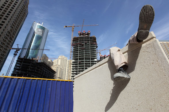 Week in Business: Labourers sit outside new high rise developments at Dubai's Marina.
