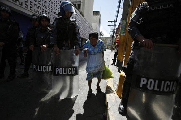 3 December 2009: Tegucigalpa, Honduras: An old woman walks between riot police officers