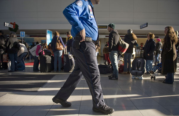 Airport security: Maryland, US: A TSA official walks by passengers in a queue