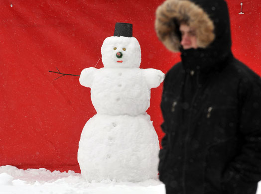 24 hours: Kiev, Ukraine: A man walks past a snowman after heavy snowfall
