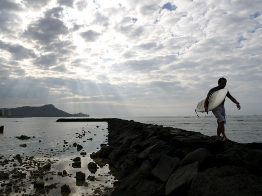 24 hours: A surfer walks with his surfboard on Waikiki Beach in Honolulu, Hawaii