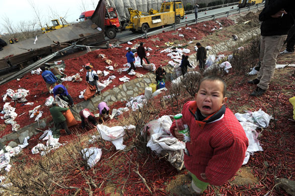 24 hours: Xiaogan, China: A child cries as villagers salvage cargo from a truck