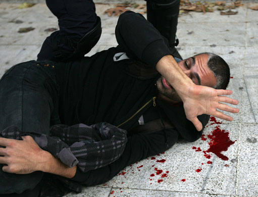 Athens demonstrations: An injured protestor is arrested by riot policemen during clashes