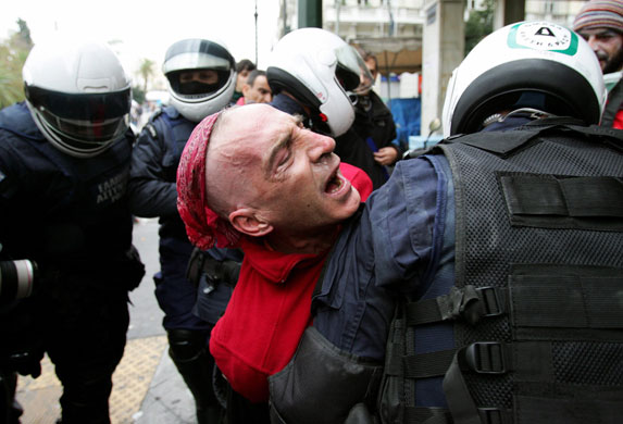 Athens demonstrations: Riot policemen detain a protester during clashes