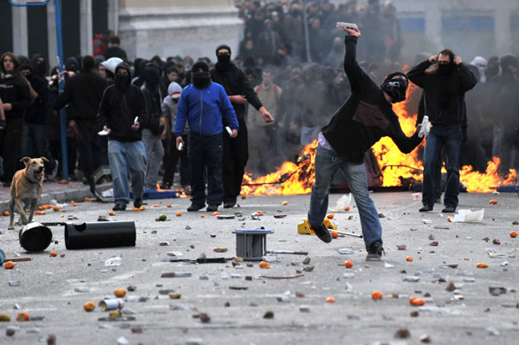 Athens demonstrations: A demonstrator throws a stone at riot police during a protest