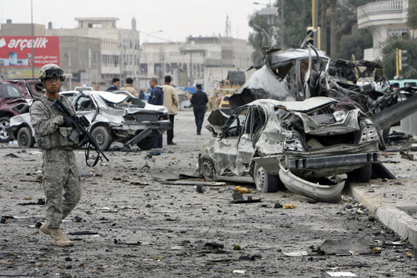 Baghdad bomb attacks: A US soldier stands guard near the wreckage of vehicles after a bomb attack