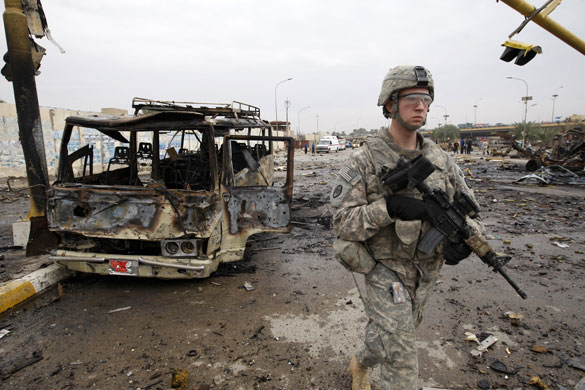 Baghdad bomb attacks: A US soldier walks past a burnt out bus at the site of a bomb attack