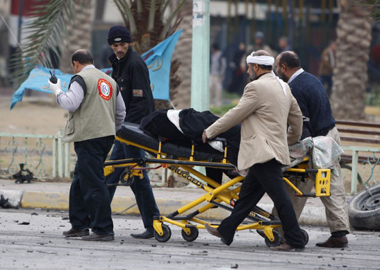 Baghdad bomb attacks: Iraqis evacuate a wounded man after a bomb blast on Cairo Street