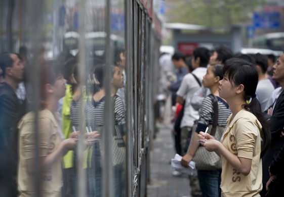 Year in Business: Job hunters check out adverts on a wall in Shenzhen, China